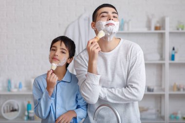 Morning of father and his little son shaving in bathroom