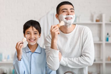Morning of father and his little son shaving in bathroom