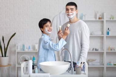 Morning of father and his little son shaving in bathroom