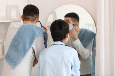 Morning of father and his little son shaving in bathroom