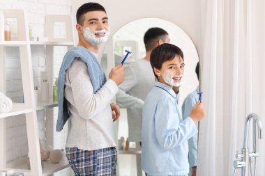 Morning of father and his little son shaving in bathroom