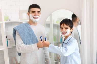 Morning of father and his little son shaving in bathroom