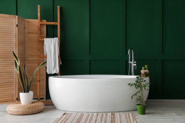 Interior of bathroom with bathtub, houseplants and ladder
