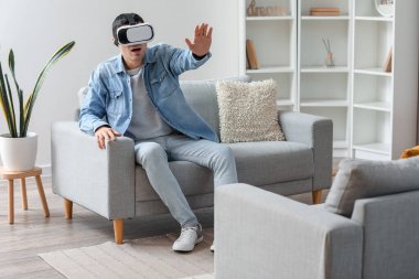 Evde VR gözlük takan genç adam.