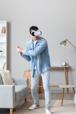 Young man using VR glasses at home