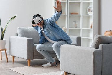 Young man using VR glasses at home