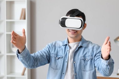 Evde VR gözlük takan genç adam.