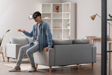 Evde VR gözlük takan genç adam.