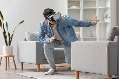 Evde VR gözlük takan genç adam.