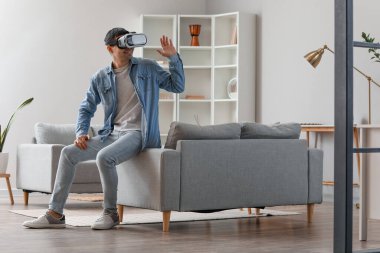Evde VR gözlük takan genç adam.