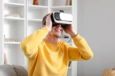 Young man using VR glasses at home