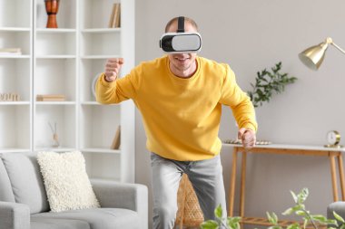 Young man using VR glasses at home