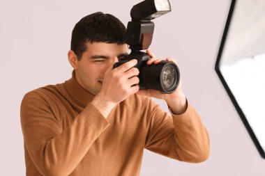 Young male photographer with professional camera in studio, closeup