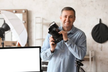 Stüdyoda profesyonel fotoğraf makinesi olan olgun bir fotoğrafçı.