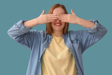 Güzel kızıl saçlı kadın mavi arka planda elleri olan gözlerini kapatıyor.