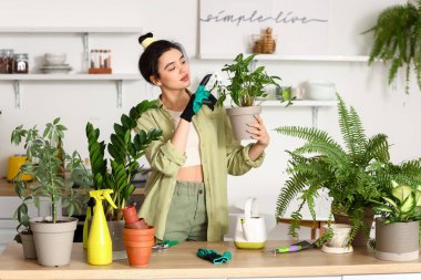 Young woman with green houseplants in kitchen