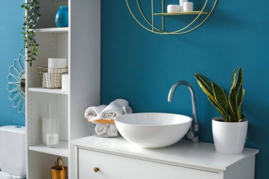 Interior of bathroom with white sink, drawers and shelving unit