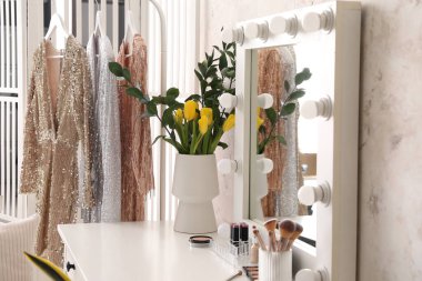 Laleli vazo, kozmetik ürünleri ve soyunma odasındaki masada ayna.