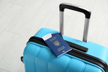 Beyaz ahşap arka planda Ukrayna pasaportlu çanta, yakın plan.