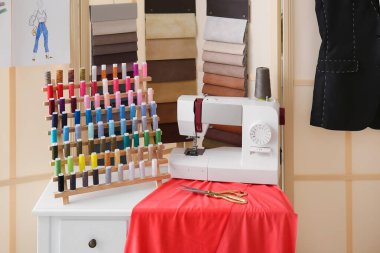 Atölyede dikiş makinesi, iplik makarası ve kumaş örnekleriyle terzinin işyeri