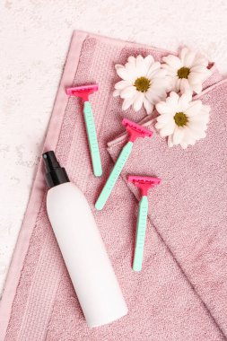 Güvenlik jiletleri, papatya çiçekleri, bir şişe deodorant ve beyaz grunge arka planda havlu.