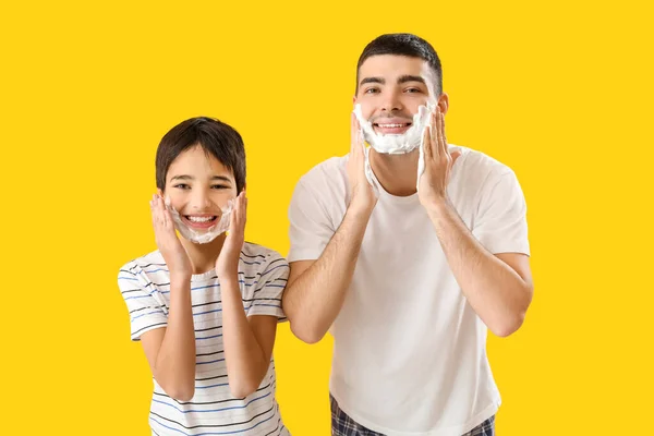 Man His Little Son Applying Shaving Foam Faces Yellow Background — Stok fotoğraf