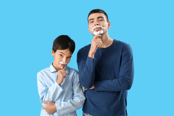 蓝色背景的男人和他的小儿子的漂亮画像 脸上有刮胡子的泡沫 — 图库照片