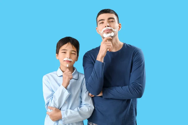 蓝色背景的男人和他的小儿子的漂亮画像 脸上有刮胡子的泡沫 — 图库照片