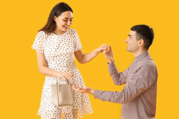可爱的年轻夫妇手拉手在黄色的背景上 — 图库照片