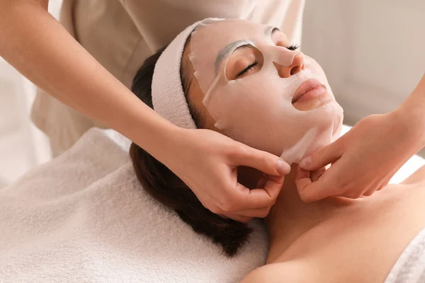 Cosmetologo Che Applica Maschera Foglio Sul Viso Della Giovane Donna — Foto Stock