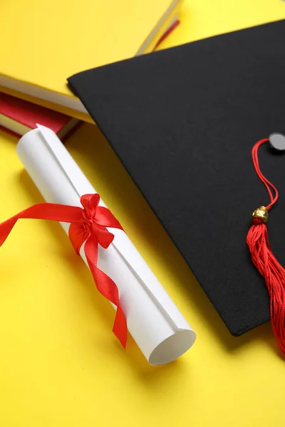 Δίπλωμα Κόκκινη Κορδέλα Καπέλο Αποφοίτησης Και Βιβλία Κίτρινο Φόντο — Φωτογραφία Αρχείου
