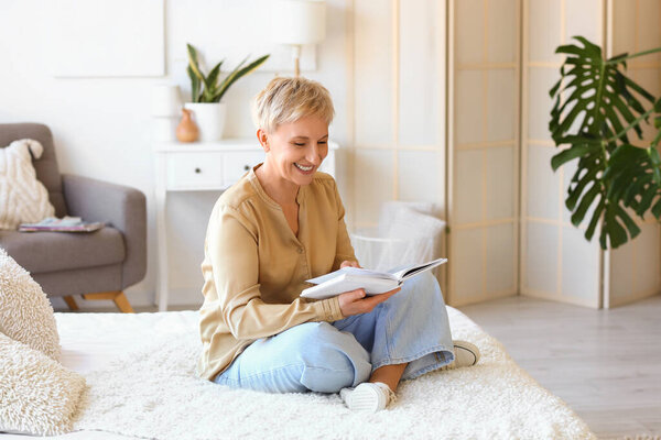 Mature woman reading book in bedroom