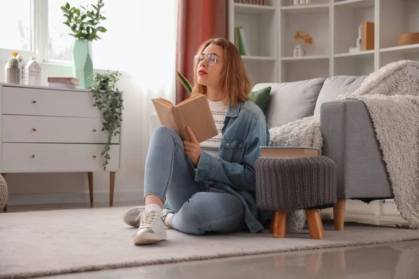 stock image Young woman reading book on floor at home