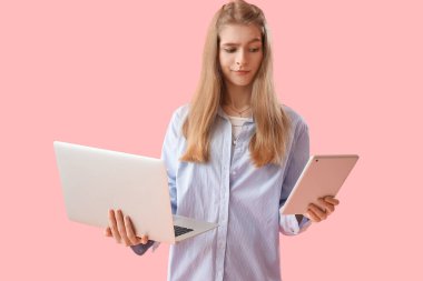 Pembe arka planda dizüstü bilgisayarı ve tablet bilgisayarı olan kadın programcı