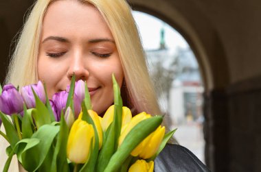 Şehir caddesinde elinde lale buketi olan genç bir kadın, yakın plan.