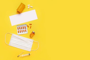 İçinde boş kağıt, ampul, haplar ve sarı arka planda tıbbi maske olan kompozisyon. Melanoma kavramı