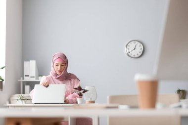 Masada dizüstü bilgisayarla çalışan Müslüman kadın programcı.