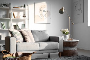 Oturma odasının içinde kanepe, raf üniteleri ve yapay bitkiler var.