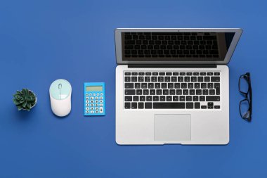 Mavi arkaplanda dizüstü bilgisayar, gözlük ve hesap makinesi ile kompozisyon