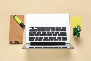 Bej arkaplanda dizüstü bilgisayar, işaret ve defter ile kompozisyon