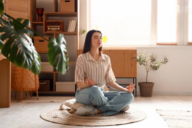 Genç kadın evde meditasyon yapıyor.