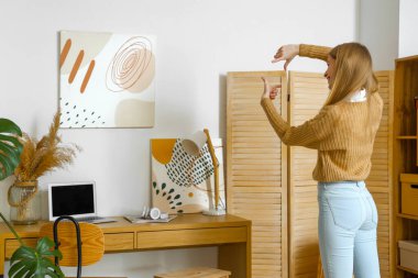 Evde resim asan genç bir kadın.