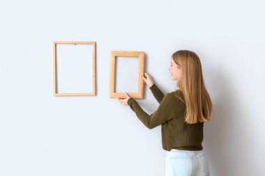 Genç bir kadın ışık duvarına çerçeve asıyor