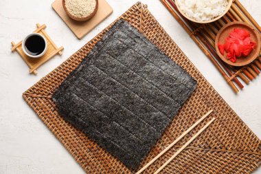 Siyah çarşaflı hasır, zencefil, soya sosu ve açık arkaplanda susam tohumları.