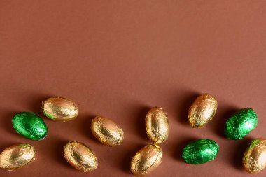 Kahverengi arka planda folyoda çikolatalı Paskalya yumurtaları