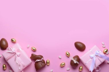 Çikolatalı tavşan, Paskalya yumurtası ve pembe arka planda hediye kutuları.