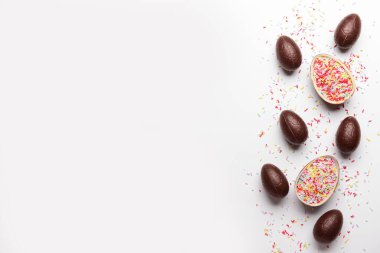 Beyaz arka plana serpiştirilmiş çikolatalı Paskalya yumurtaları.