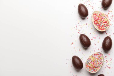 Beyaz arka plana serpiştirilmiş çikolatalı Paskalya yumurtaları.