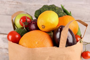 Tahta arka planda sebzeli kağıt torba.