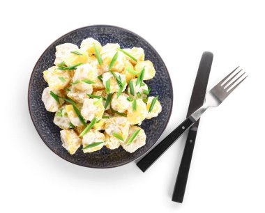 Beyaz arka planda yeşil salatalı lezzetli patates salatası.